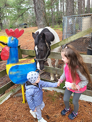 A young girl and young boy visit a horse at a farm exhibita horse