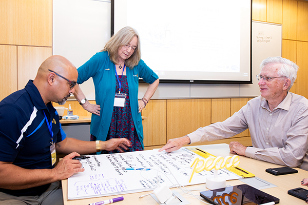 two peace activators discussing words on a whiteboard at a table