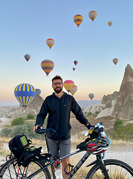 Parent on bicycle with balloons rising in background