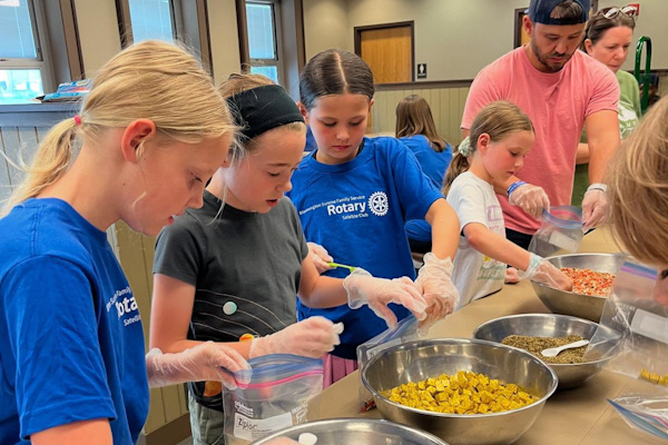 Rotary members and their children prepare snack packs.