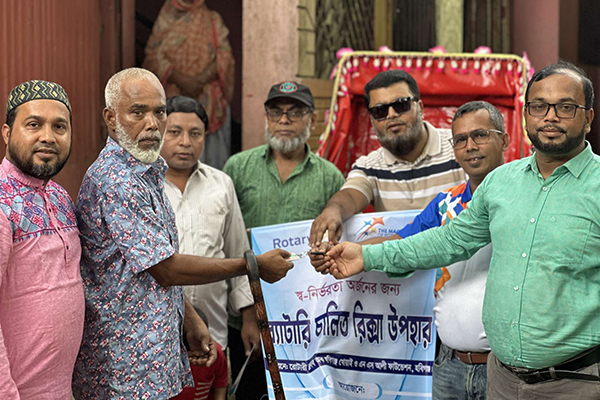 Rotary members stand in front of a rickshaw they are gifting to a low-income individual