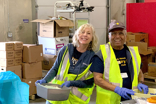 Two volunteers in yellow vests sort items for an EPIC Day of Service event.
