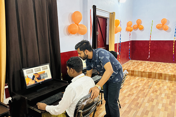 The author assists another young person at a copmuter screen.
